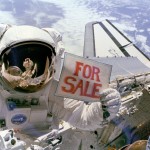 Satellites For Sale Astronaut Dale A. Gardner, having just completed the major portion of his second extravehicular activity (EVA) period in three days, holds up a "For Sale" sign.