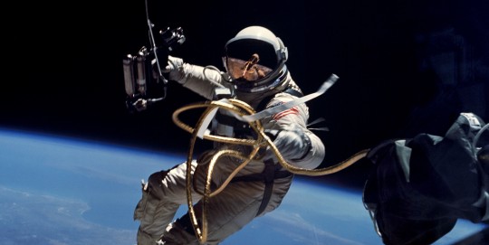 An astronaut in space with Earth below and connected by an umbilical.