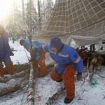 Astronauts and cosmonauts chopping wood for a fire.
