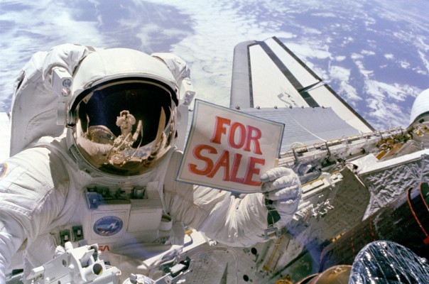 Astronaut Dale A. Gardner, having just completed the major portion of his second extravehicular activity (EVA) period in three days, holds up a "For Sale" sign.