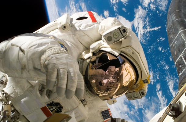 A NASA Extravehicular Mobility Unit (EMU) with earth in the background.